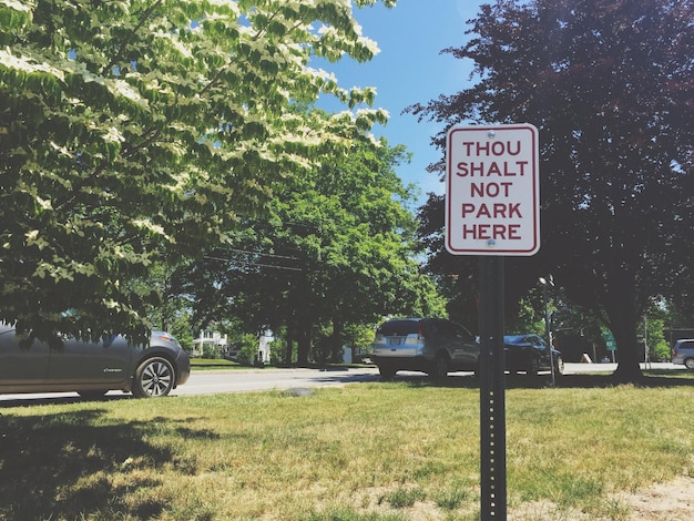 Segnale di avvertimento sul campo erboso contro le macchine parcheggiate dagli alberi