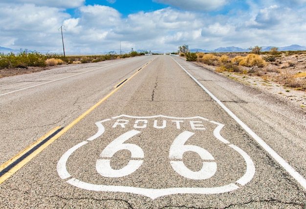 Segnale stradale di Route 66 con il fondo del cielo blu. Strada storica senza nessuno. Classico concetto di viaggio e avventura in chiave vintage.