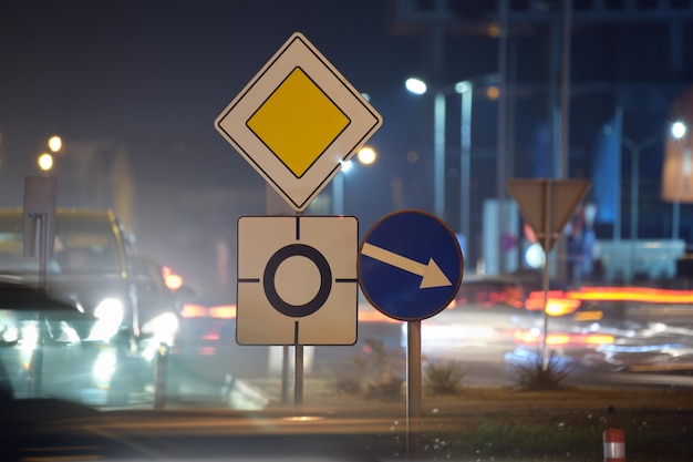 Segnaletica stradale rotonda con auto sfocate sul traffico cittadino di notte Concetto di trasporto urbano