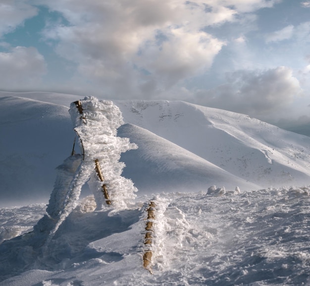 Segnali coperti di neve e montagne invernali alla luce del sole dell'ultima sera Magnifico crepuscolo ventoso sulle cime sopra la pittoresca stazione sciistica alpina Concentrarsi sulle montagne lontane