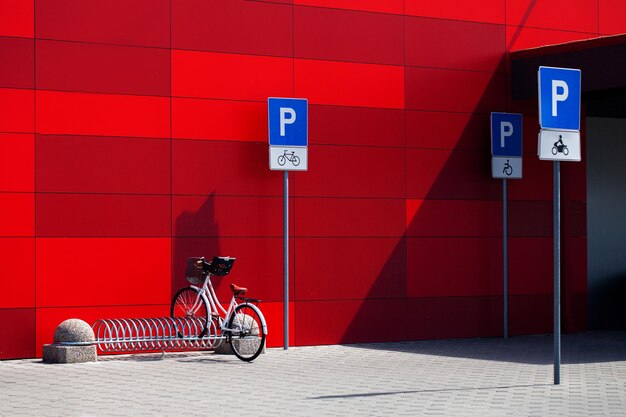 Segnali di parcheggio per biciclette e biciclette su sfondo rosso della parete