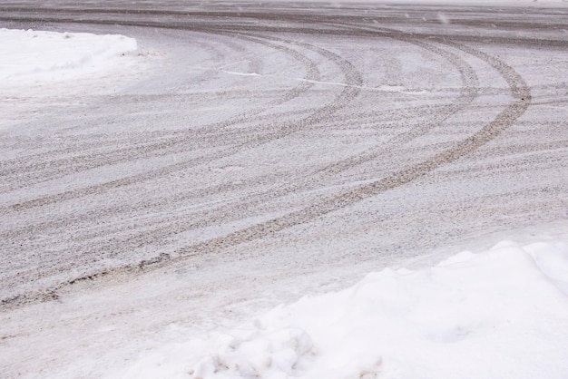 Segni di neve e ruote di auto sulla strada