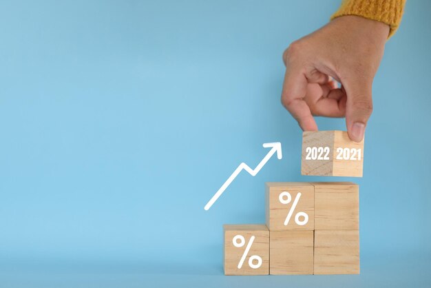 Segni e simboli di blocco di legno lanciati a mano con segno di percentuale e freccia su tassi di interesse di crescita finanziaria e aziendale e interessi sui tassi ipotecari sul concetto di inflazione degli investimenti