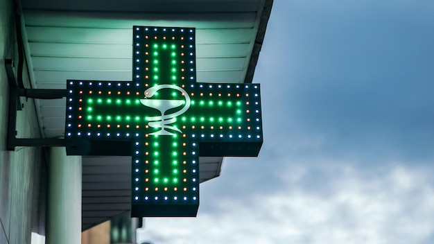 Segno al neon della croce verde medica del negozio di farmacia