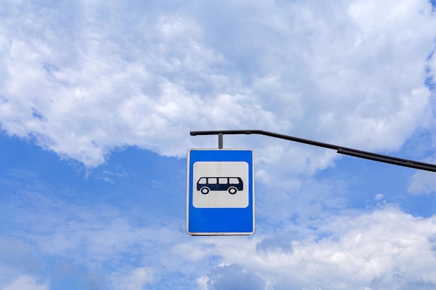 segno della fermata dell'autobus sullo sfondo di un cielo nuvoloso blu chiaro. un segno dall'alto. cartello stradale blu