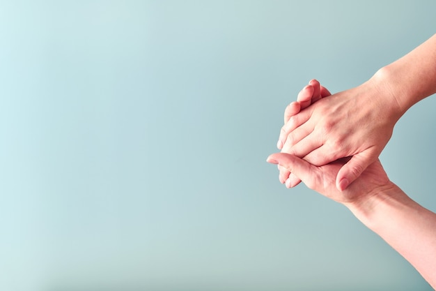 Segno di stretta di mano femminile su sfondo azzurro. Messa a fuoco selettiva. Modello. Copia spazio.