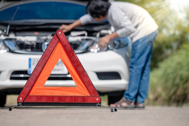 Segno e autista di arresto di emergenza vicino all&#39;automobile rotta sulla strada.