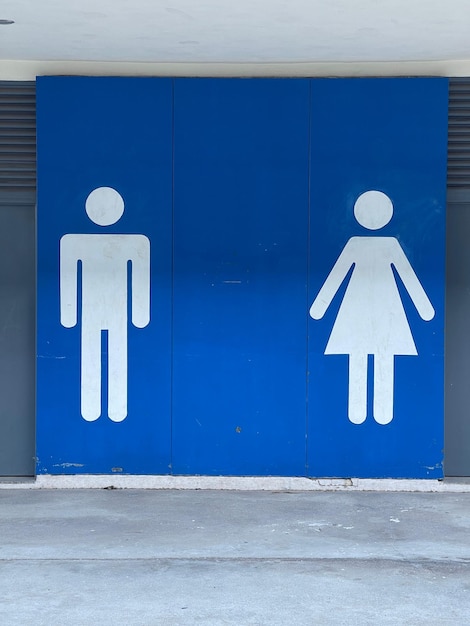 Segno informativo di uomo e donna sulla parete bianca