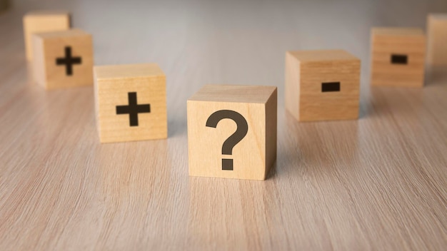 Segno punto interrogativo più segno meno sulle facce di un cubo di legno mini cubi di legno su sfondo di legno