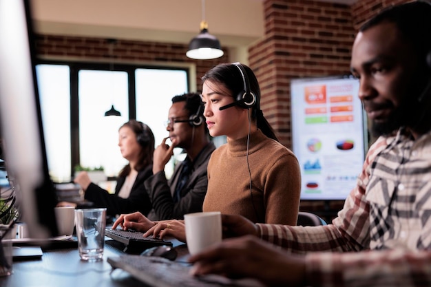 Segretaria che risponde alla chiamata di assistenza telefonica dal cliente alla reception, lavorando presso il centro di assistenza clienti. Operatore asiatico che fornisce assistenza telemarketing su rete di telefonia remota.