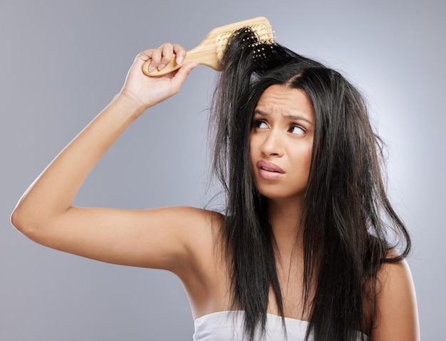 Segui le buone pratiche per la cura dei capelli per evitare danni Foto in studio di una giovane donna con i capelli danneggiati in posa su uno sfondo grigio