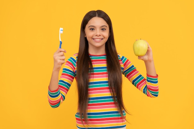 Seguire l'igiene orale Ragazza felice tenere mela e spazzolino da denti Igiene orale Cure dentali Vitamine per denti sani e forti