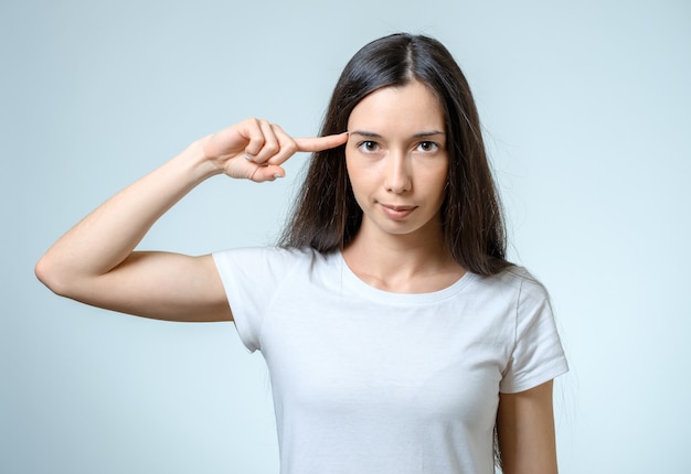 Sei pazzo? Giovane bella donna che gesturing dito contro il suo tempio