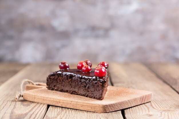 Selembar kue bebas gluten dalam cokelat, dihiasi dengan cranberry, di atas papan dapur, di atas latar belakang buram. Makanan sehat.