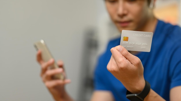 Seleziona focus sulla mano che tiene la carta di credito e utilizza lo smartphone per effettuare ordini tramite iInternet o pagamento online