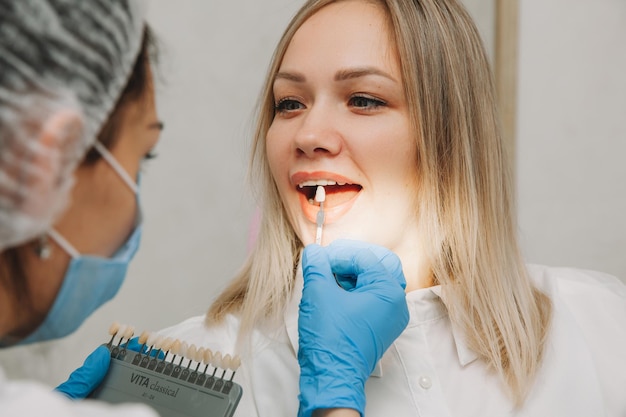 Selezione del colore dei denti corretto per lo sbiancamento cosmetico professionale dal dentista. il medico seleziona i denti per il paziente.