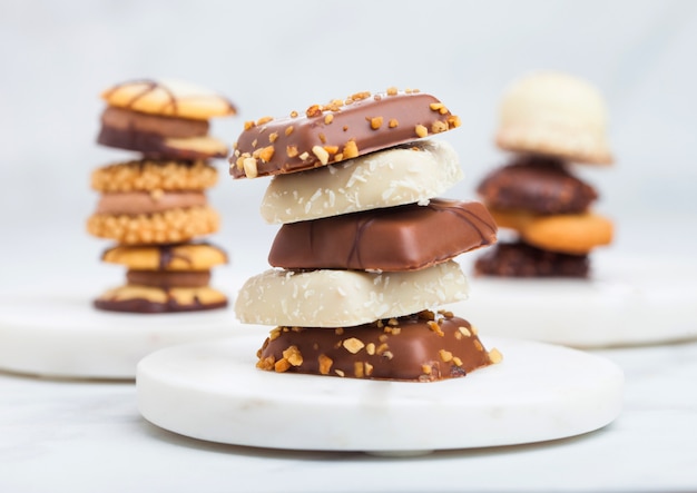 Selezione di biscotti belgi di lusso al cioccolato e biscotti su sottobicchieri e tavolo da cucina in marmo.