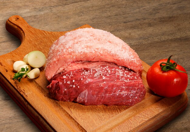 Selezione di carne cruda sul tagliere di legno.