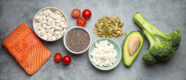 Selezione di prodotti alimentari sani se una persona ha il diabete pesce salmone broccoli fagioli di avocado verdure semi su sfondo grigio dall'alto Dieta sana per il diabete