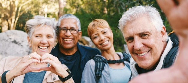 Selfie della natura e amici anziani che fanno un'escursione insieme in una foresta durante un'avventura all'aria aperta Sorriso felice e ritratto di un gruppo di anziani che fanno trekking nei boschi per il benessere, la salute e l'esercizio fisico