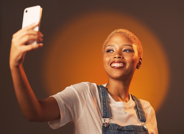 Selfie di bellezza e donna di colore in studio per il divertimento del trucco e l'estetica dei riflettori su sfondo sfumato Ragazza dei social media e influencer della moda sorridono per l'immagine del profilo del blog o l'aggiornamento della home page