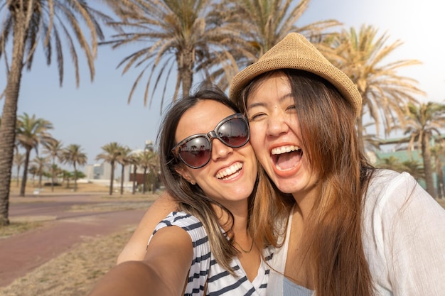 Selfie di due amici felici che ridono e si tengono in spiaggia Ragazze allegre che si abbracciano