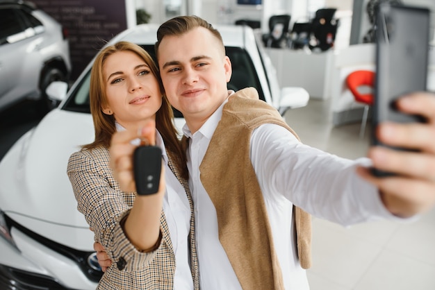 Selfie di famiglia in concessionaria. La giovane coppia felice sceglie e acquista una nuova auto per la famiglia.