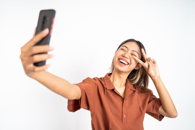 Selfie di giovane donna utilizzando la fotocamera del telefono cellulare con il segno v