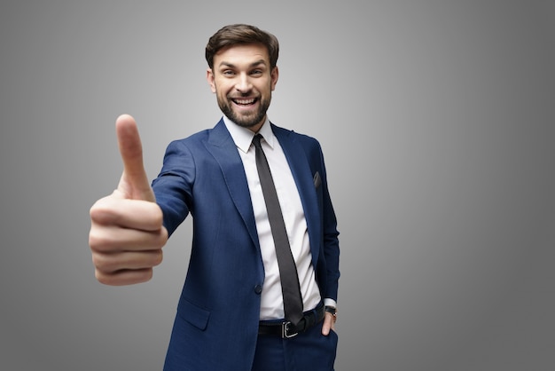 selfie di uomo d'affari giovane salendo il pollice sul muro grigio