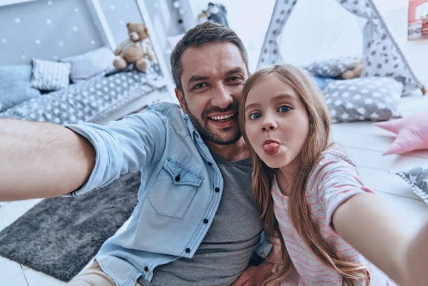 Selfie divertente con papà. Autoritratto del giovane padre e della sua piccola figlia che si fanno selfie