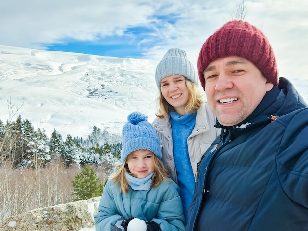 Selfie mamma papà e figlia in una passeggiata tra le montagne innevate