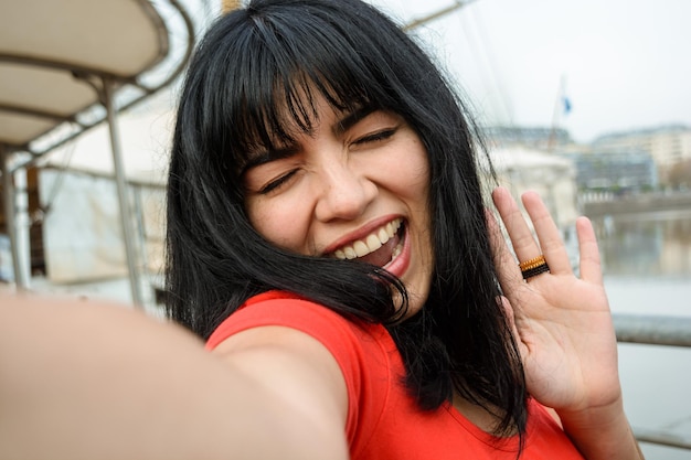 Selfie ritratto di giovane donna latina di etnia venezuelana vestita di rosso sorridente felice all'aperto