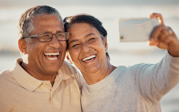 Selfie sulla spiaggia delle coppie anziane e sole estivo con felicità per blog di viaggio e post sul web Donna anziana e sorriso per la fotografia sull'immagine del profilo di una vacanza romantica e sull'app dei social network