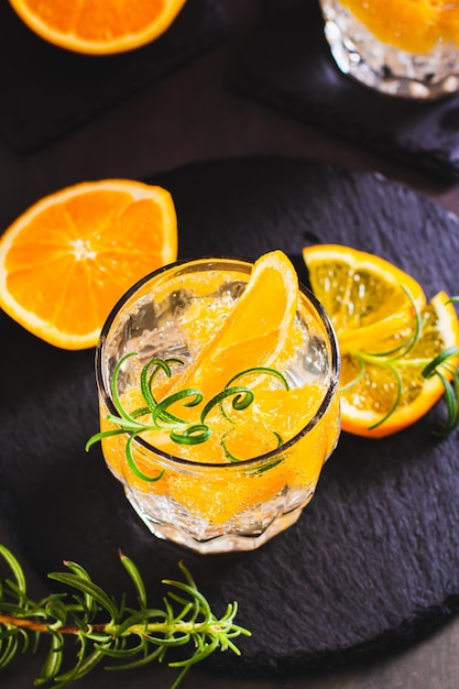 Seltzer duro con arancia ghiacciata e rosmarino in un bicchiere sul tavolo vista verticale