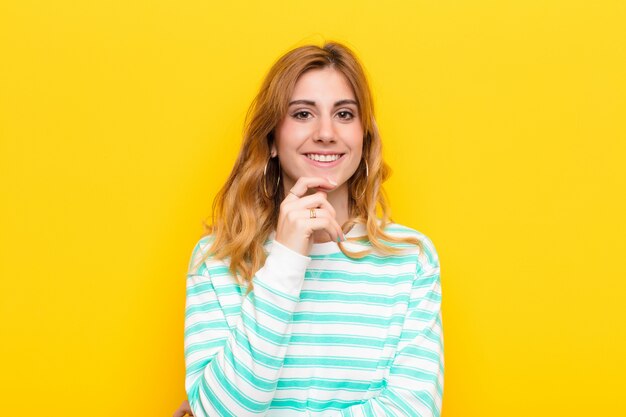 sembra felice e sorride con la mano sul mento, chiedendosi o facendo una domanda, confrontando le opzioni