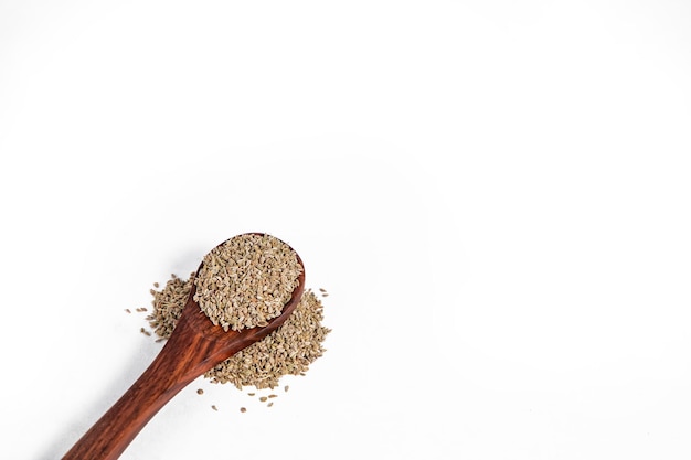 Semi di Ajwain organici marroni crudi in cucchiaio di legno su fondo bianco