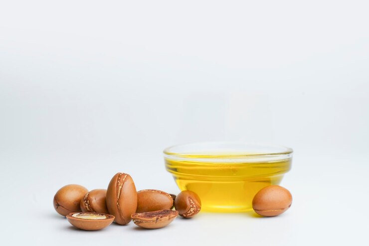 Semi di Argan e olio isolato su uno sfondo bianco Noci di olio di Argan con piante Cosmetici e naturali