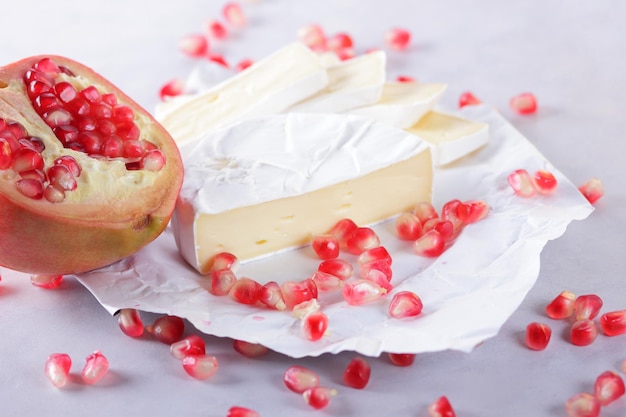 Semi di camembert e melograno su carta pergamena su sfondo chiaro Delizioso formaggio sul primo piano del tavolo Un ottimo prodotto per la colazione