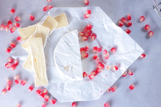 Semi di camembert e melograno su carta pergamena su sfondo chiaro Delizioso formaggio sul primo piano del tavolo Un ottimo prodotto per la colazione