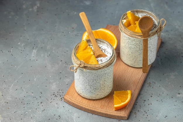 Semi di Chia con yogurt senza lattosio in vetro decorato con agrumi Yogurt con semi di chia su sfondo grigio superfood sano Cibo sano posto per il testo