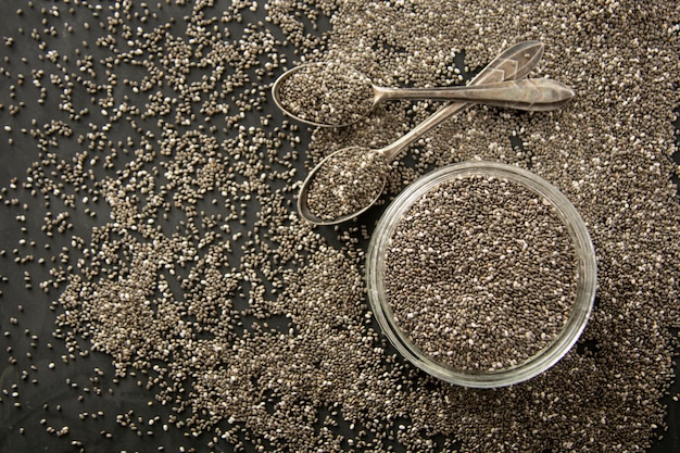 Semi di Chia in ciotola di vetro isolata su fondo di legno, fuoco selettivo. Sfondo scuro