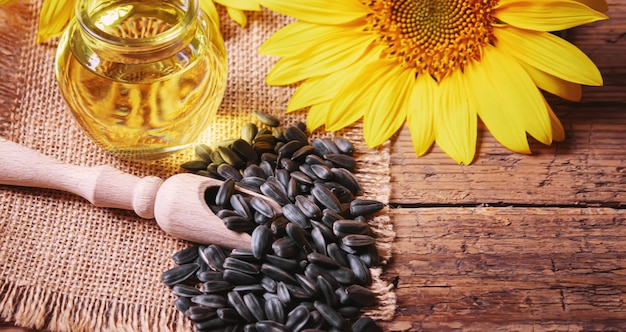 Semi di girasole e bottiglia di olio su fondo di legno vecchio. Messa a fuoco selettiva.natura