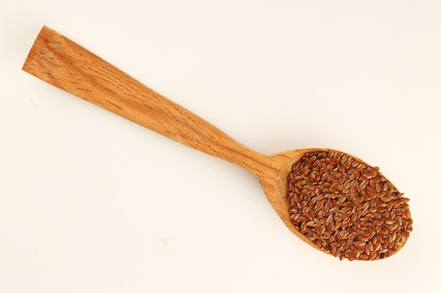 Semi di lino in un cucchiaio su una superficie bianca