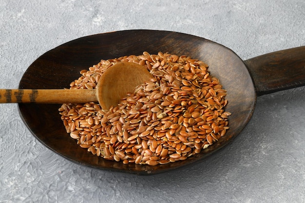 Semi di lino Polvere di semi di lino in un cucchiaio di legno In piedi su uno sfondo di legno