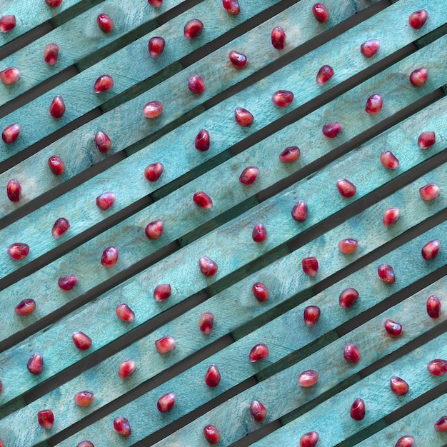 Semi di melograno rosso su sfondo turchese, trama linea diagonale, vista dall'alto