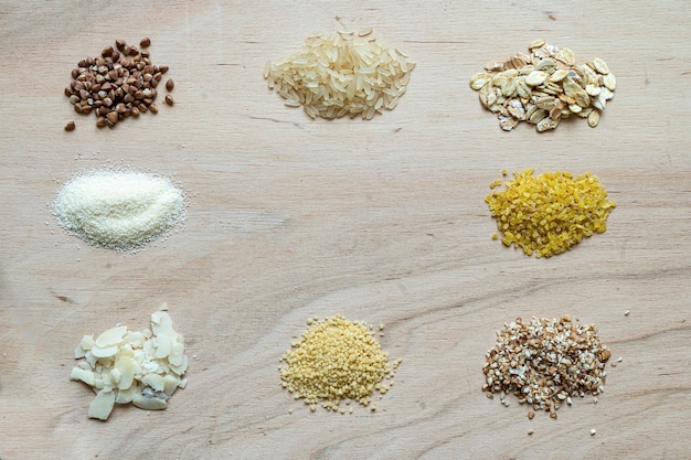 Semi di porridge di cereali assortiti impostato su uno sfondo di legno: grano saraceno, riso, semolino, grano, cuscus, farina d'avena