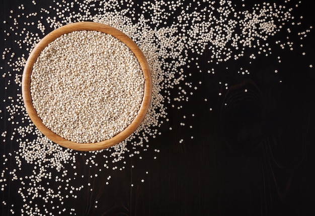 Semi di quinoa bianchi secchi su fondo di legno nero