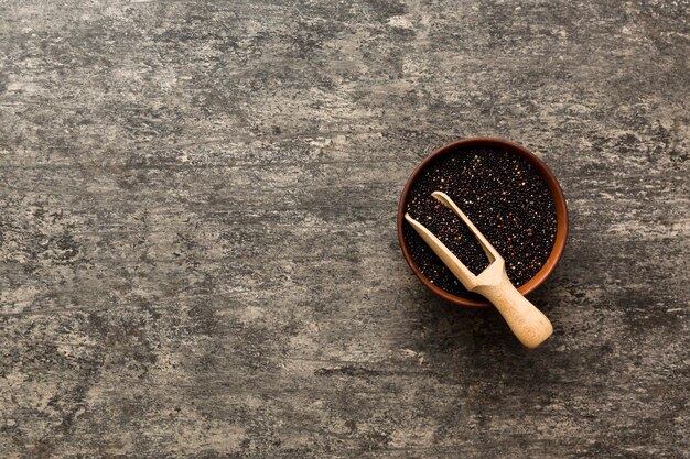 Semi di quinoa in ciotola e cucchiaio su sfondo colorato Kinwa sano in una piccola ciotola Superfood sano