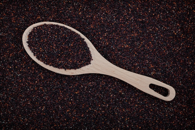 Semi di quinoa nera peruviana sullo sfondo del cucchiaio di legno