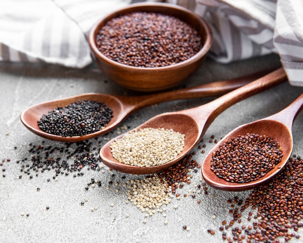 Semi di quinoa rossi, bianchi e neri su uno sfondo di cemento